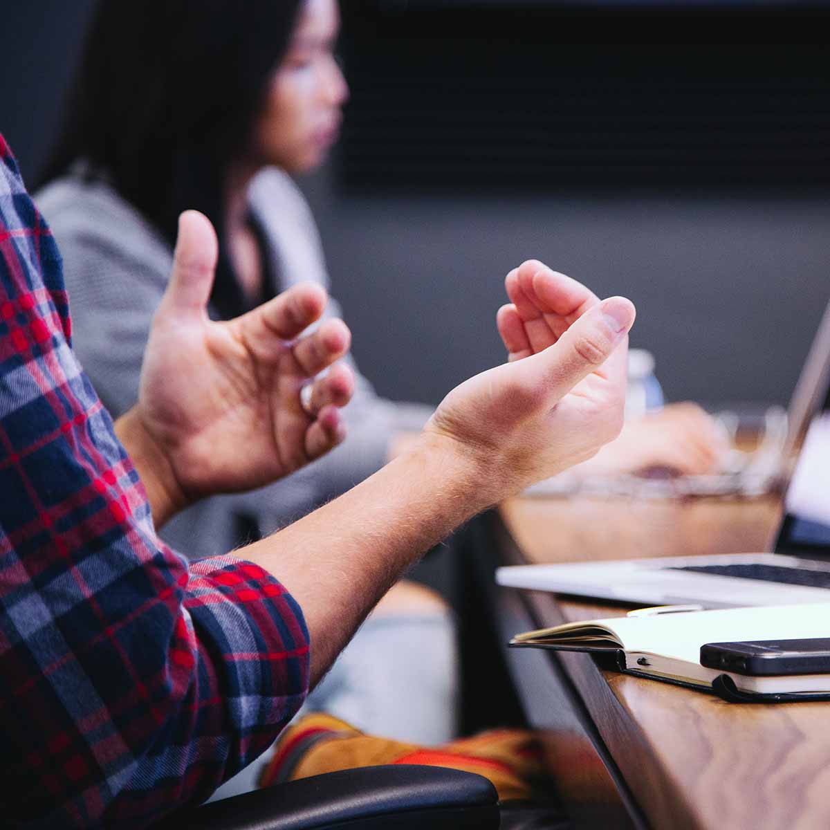 A man gestures with his hands to those in the office.